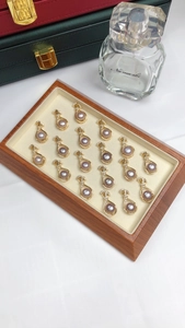 Detail of purple pearl rings with gold bow accents and diamonds on dark wood tray