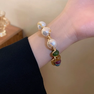 Close-up of handmade gold wire-wrapped bracelet with baroque pearls and colorful beads