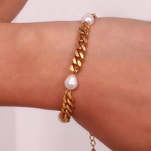 Detail of gold Cuban chain bracelet with three white pearls on a model's wrist