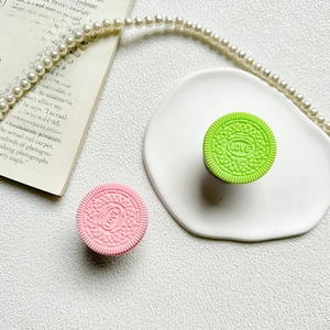 Detail of pink and green biscuit-shaped phone grips with LOVE relief on a white plate