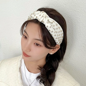 Close-up of white knotted headband with gold-set rhinestones on an elegant model