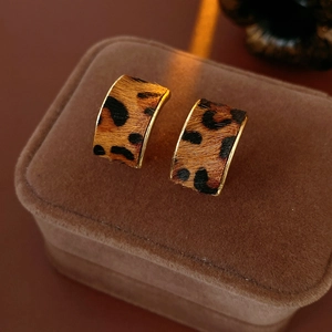 Gros plan de boucles d'oreilles léopard vintage sur un écrin en velours marron