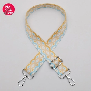 Detail of adjustable bag strap featuring yellow and blue geometric jacquard patterns with silver buckles