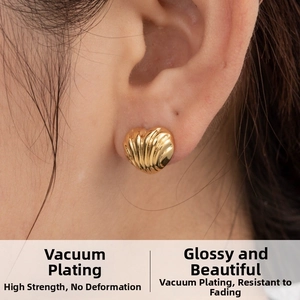 Détail de boucles d'oreilles cœur dorées avec texture coquillage et placage sous vide