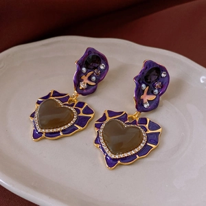 Macro detail of vintage heart drop earrings with purple enamel and zircon inlay