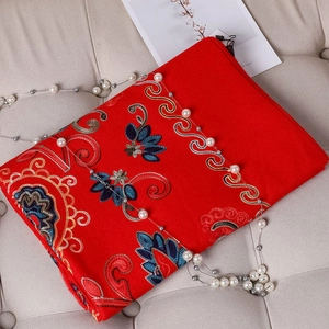 Detailed view of red winter scarf featuring intricate floral embroidery and soft fringe