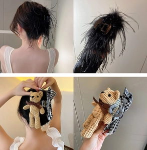 Detail view of black feather hair claw and khaki knit bear hair clip with bow