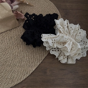 Detail view of black and white cotton lace hair ties on a rustic woven mat surface