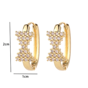Detail view of gold bow earrings with cubic zirconia including 2cm and 1cm size marks