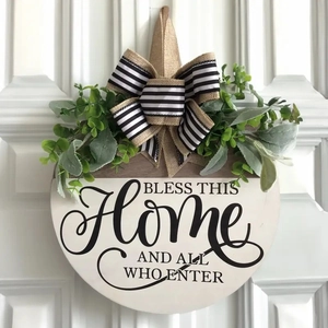 Close-up of wooden welcome wreath with greenery and bow on white front door