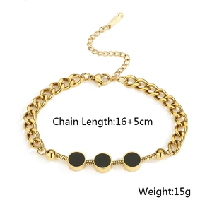 Detail view of a gold-plated stainless steel chain bracelet with black circular charms