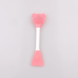 Detail of pink silicone facial brush with bear-shaped massage bristles and mask spatula