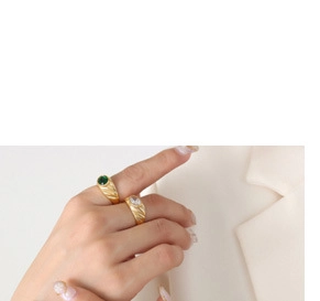 Gros plan de bagues plaquées or avec zircons blancs et verts sur la main du mannequin