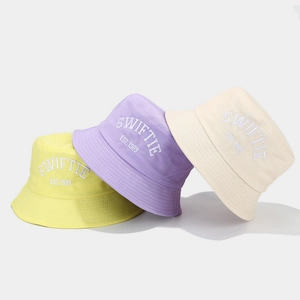 Three Swiftie 1989 embroidered cotton bucket hats in yellow, purple, and cream colors