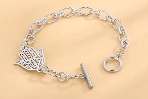 Gros plan du bracelet à chaîne argentée avec pendentif main de fatma et fermoir à bascule