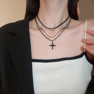 Dettaglio collana multistrato gotica con croce di cristallo su modella in abito nero