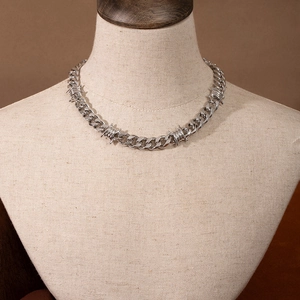 Close-up of silver thorn Cuban link chain necklace on a beige fabric neck display bust