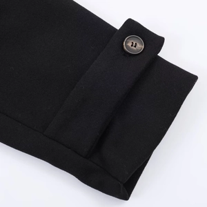 Détail du poignet d'un manteau noir en laine avec un bouton texturé marron foncé