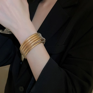 Detail of layered gold spiral bracelet with threaded texture on model wrist