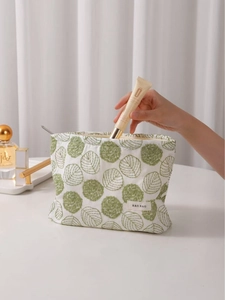 White linen makeup bag with green floral embroidery and top zipper closure