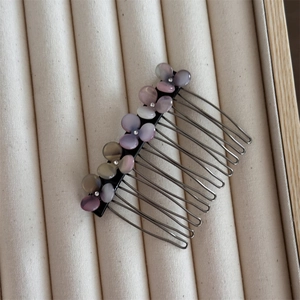 Close-up of hair comb with purple and pink floral gems on a soft beige velvet background