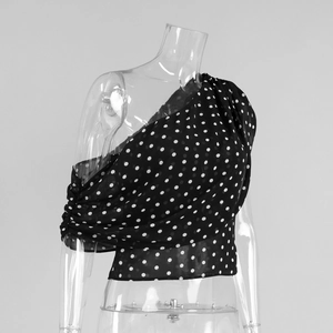 Détails du tissu en mousseline noire à pois blancs avec coutures froncées sur le côté