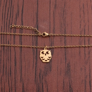 Polished gold stainless steel owl pendant necklace with hollow design on dark wood background