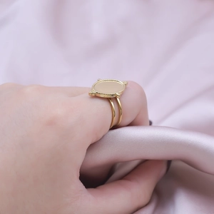 Detailed shot of a gold oval signet ring with beaded borders on soft pink silk