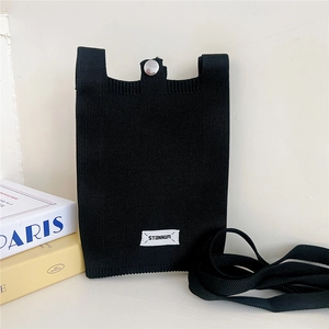 Detail of black knitted phone bag with silver snap button and Stanum logo tag