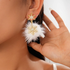 Close-up of golden snowflake earrings with a white fur ball and sparkling rhinestones