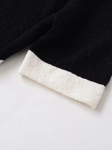 Detail of the high-quality contrast stitching and texture on black knit short sleeve jacket
