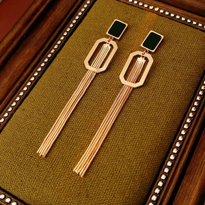 Détail de boucles d'oreilles dorées à franges avec clous noirs et cadres géométriques