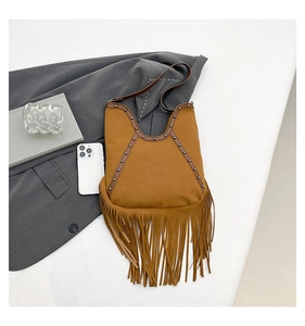 Close-up of brown suede fringe tote bag with rivet details and embossed sun face pattern