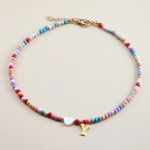Detail of colorful beaded necklace featuring a shell heart and a golden letter Y pendant