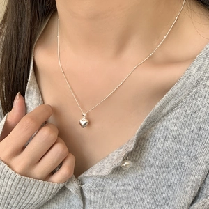 Detail of silver heart pendant necklace on a thin beaded chain with a polished finish