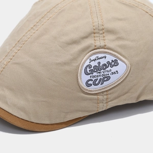 Detail of khaki cotton beret showing premium stitching and a vintage embroidered patch