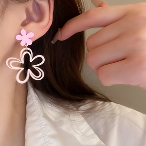 Pink minimalist hollow flower drop earrings with two-tier design worn by a model
