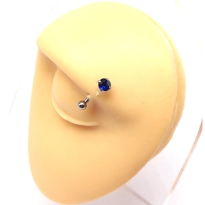 Macro shot of curved stainless steel eyebrow piercing with blue zircon stone on model