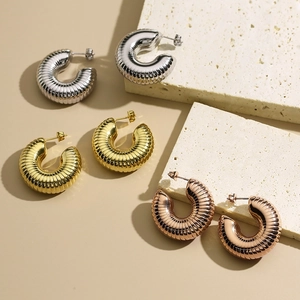 Detailed macro view of 18K gold-plated C-shaped earrings in gold, silver, and rose gold