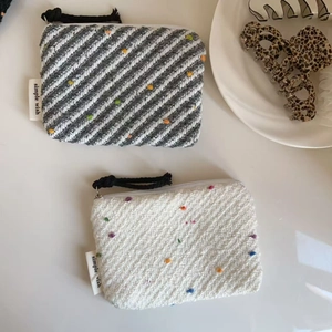 Dettaglio di mini portamonete in maglia a pois colorati con cerniera ed etichetta in tessuto