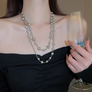 Close-up of layered silver star pendant necklace on a model wearing black off-shoulder top