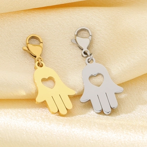 Détail de breloques main de Hamsa en or et argent avec cœur sur tissu en soie