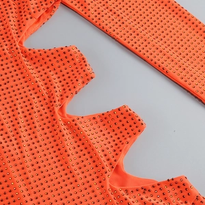 Détail macro d'une robe orange avec strass brillants et découpes de design tendance