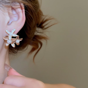 Close-up of 18K gold-plated flower earrings with pearls on model's ear