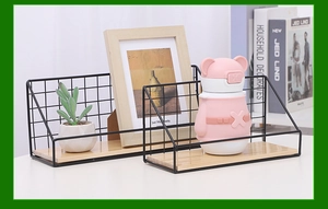 Detail view of black iron mesh wall shelves with wooden bases holding small plants and decor