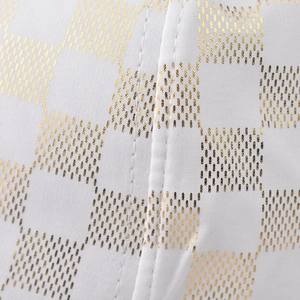 Macro detail of white satin fabric with golden polka dot pattern and double-stitch seam