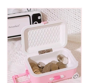 Pink suitcase-shaped piggy bank filled with coins showing storage capacity