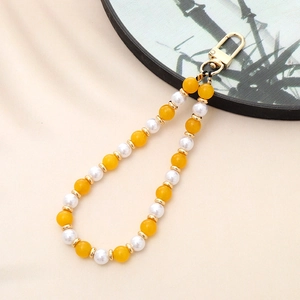 Detail of yellow and white natural stone beaded phone strap with golden metal clasp