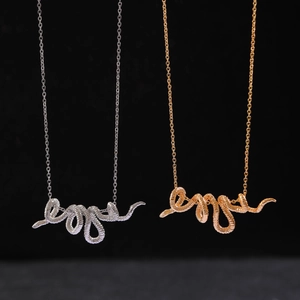 Punk style coiled snake pendant necklaces in gold and silver finishes on black background