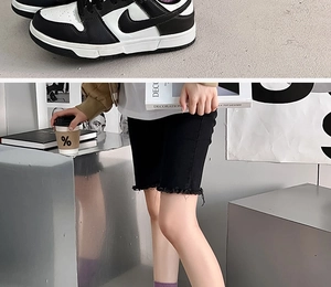Detail of stylish black crew socks with contrast letter embroidery and denim shorts